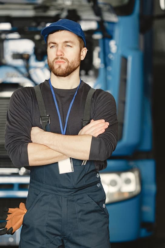 Driver standing with arms crossed in front of a truck